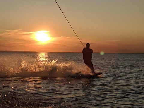 Tim wakeboarding across calm water at sunset